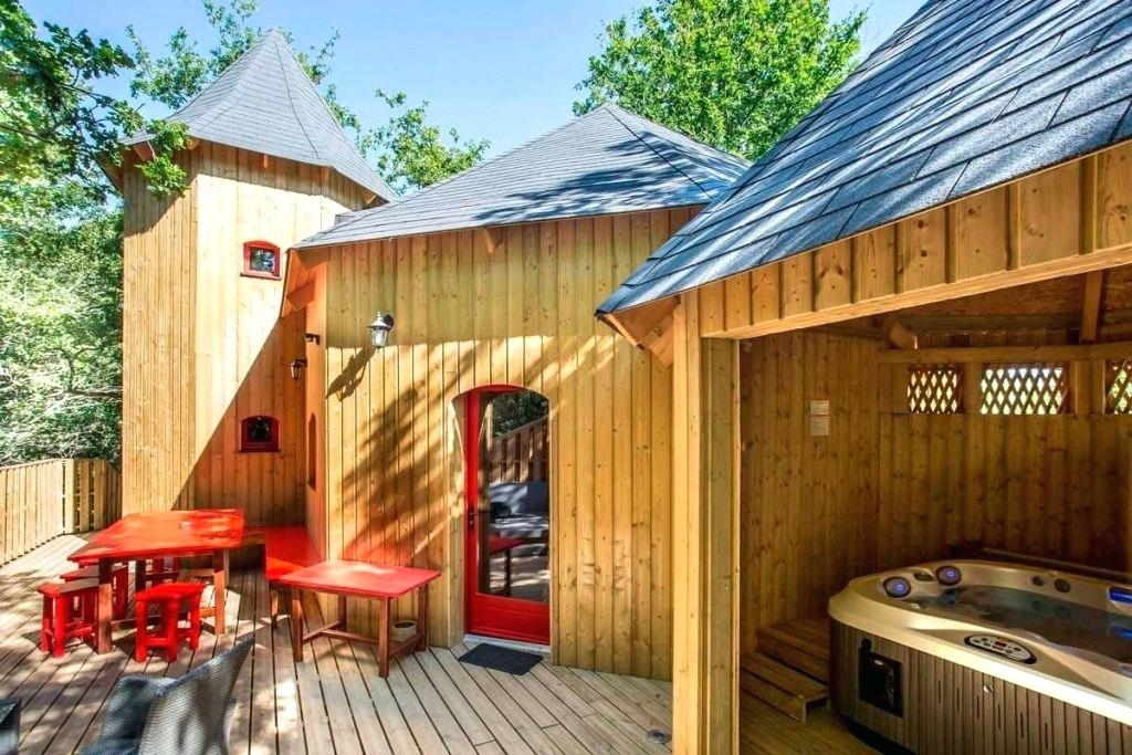 This outdoor hot tub is placed under a pergola, installed atop a deck